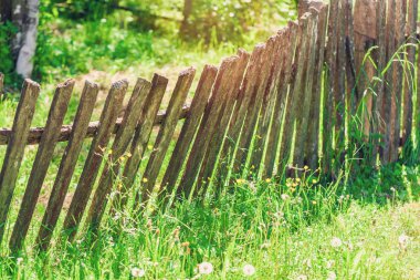 Çimenlerin üzerinde düşen eski ahşap köy çit.