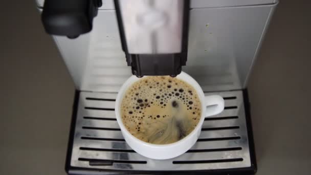 Gocce di caffè cadono in tazza piena bianca su supporto metallico — Video Stock