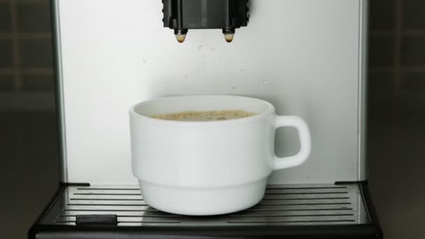 Gocce di caffè cadono dal dispenser in tazza bianca sul supporto — Video Stock