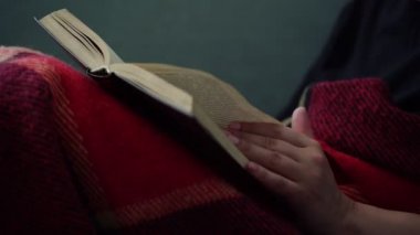 kadın kırmızı ekose yakın kanepede oturan kitap sayfaları çevirir