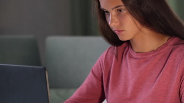 Улыбающаяся брюнетка в фиолетовой толстовке смотрит на современный ноутбук — стоковое видео