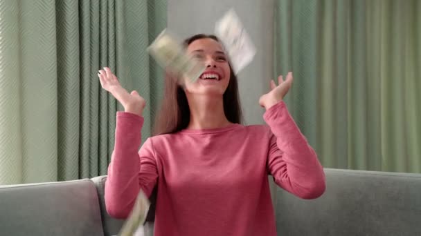 Meisje zit op de Bank onder de bankbiljetten regen vallen van het plafond — Stockvideo