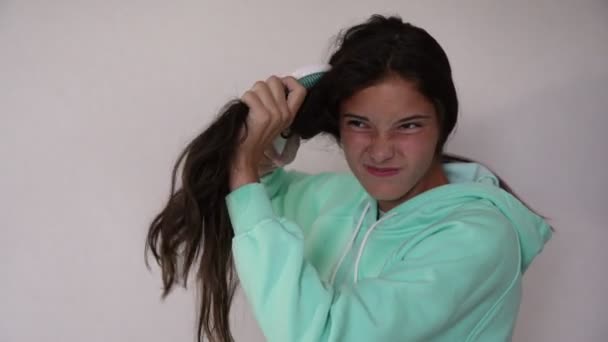 Young angry brunette tries to comb long hair with hairbrush — Stock Video