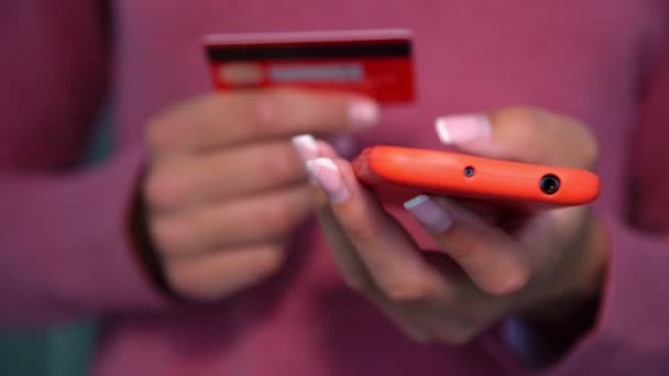 Lady holds red credit card and inputs data into smartphone — Stock Video