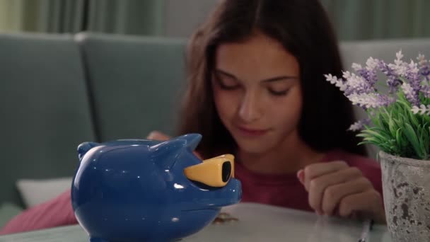 Привлекательная брюнетка берет монеты кладет в голубой копилку — стоковое видео