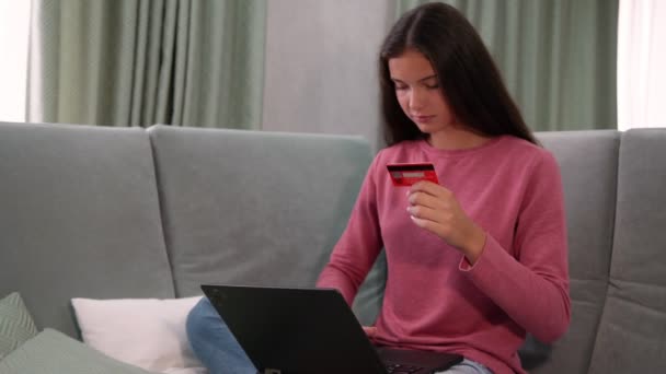 Симпатичная дама держит кредитную карту и типы на современном ноутбуке — стоковое видео