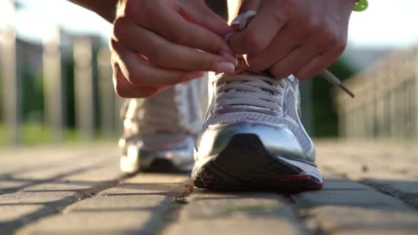 Junge fitte Frau bindet Turnschuhschnürsenkel auf grauer Straße — Stockvideo