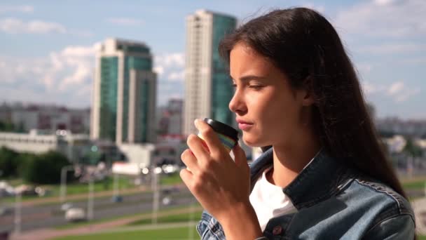 Aantrekkelijke tiener drinkt koffie en bewondert stadsgezicht — Stockvideo