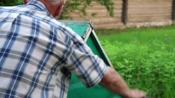 Senior man in gestreepte shirt bochten houten goed handvat — Stockvideo