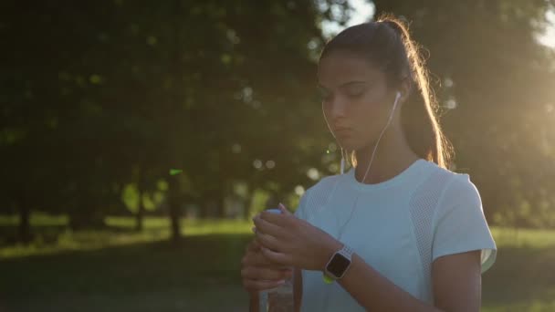 Sportieve dame in t-shirt drinkt water uit plastic fles — Stockvideo