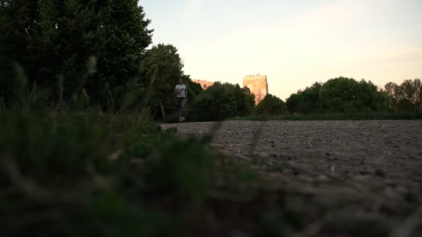 Fille athlétique court le long de la route de parc gris contre la construction — Video