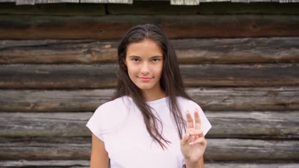 Långhårig brunett i vit t-shirt visar fredssymbol — Stockvideo