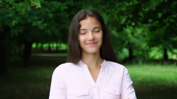 Morena sonriente en blusa blanca posa y fija el pelo largo — Vídeo de stock
