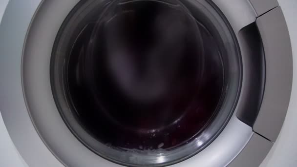 Clothes objects rotate in white washing machine closeup — Stock Video