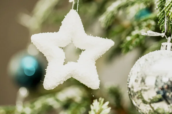 close-up big toy white star hanging on Christmas tree branch