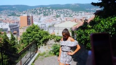 kız şehir manzarasına karşı fotoğraf çekerken arkadaşı önünde poz veriyor