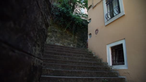 Ladies climb down stone steps walking along narrow street — Stock Video