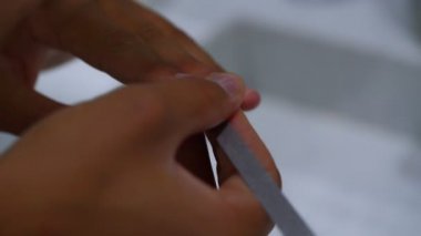 Bronzlaşmış kadın manikür için tırnak törpüsü kullanıyor.