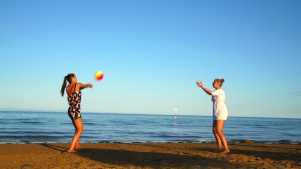 Szőke és barna lányok játszanak röplabda strandon közel a tengerhez — Stock videók