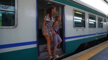 Trenden inen genç kızlar istasyonu işaret ederek el ele tutuşuyorlar.