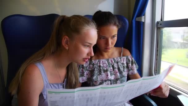 Teen girls look at map and talk riding intercity train — Stock Video