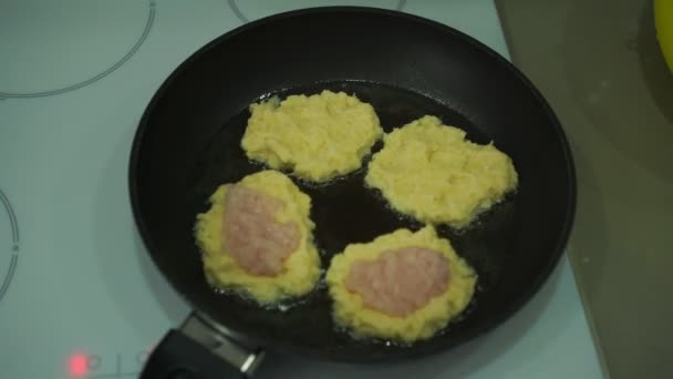 Домохозяйка готовит картофельные блинчики с мясом на сковородке — стоковое видео