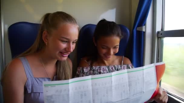 Χαριτωμένο κορίτσι έφηβοι μιλούν και να εξετάσουμε χάρτη πηγαίνει στο τρένο — Αρχείο Βίντεο