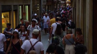 Venedik 'te turist kalabalığı cadde boyunca gölgede yürüyor.