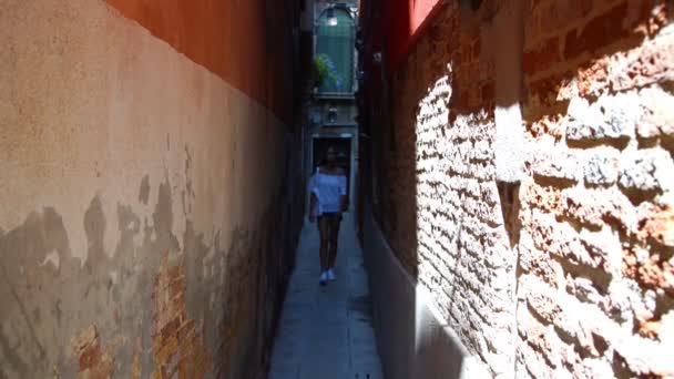 Flicka promenader till kameran på smal skuggig gata i Venedig — Stockvideo