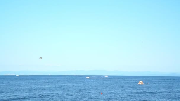 Białe łodzie motorowe pływają w morzu przeciwko górom i niebu — Wideo stockowe