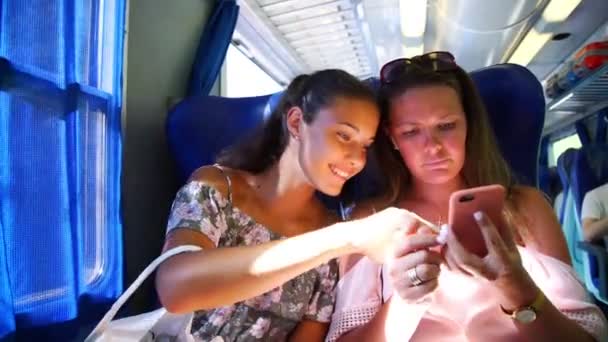 Cute girl points to phone and laughs with mother in pink — Stock Video