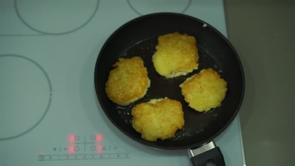 Картофельные блинчики в сковородке на современной электрической плите — стоковое видео