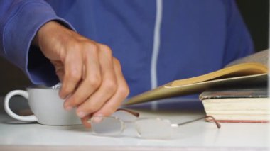 Son sınıf öğrencisi gözlük takıp kitap sayfalarını kapatıyor.