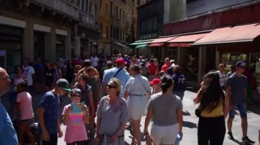 Turistler kalabalık Venedik meydanında eski evlerle yürüyor