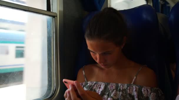 Дівчина панує в Інтернеті по телефону, проходячи залізничну станцію крупним планом — стокове відео
