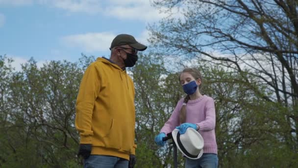 Молодая девушка в одноразовой маске и перчатках показывает путь к мужчине — стоковое видео