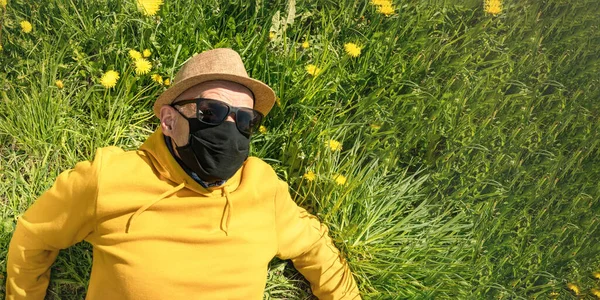 Homem idoso em máscara preta e óculos de sol se levanta da grama — Fotografia de Stock