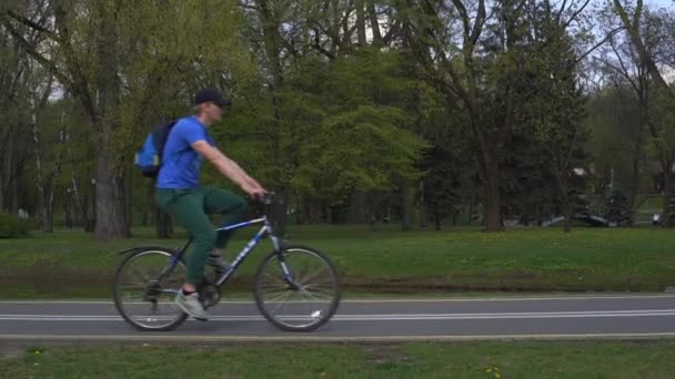 Várias pessoas andam de bicicleta e scooter ao longo da estrada de asfalto — Vídeo de Stock