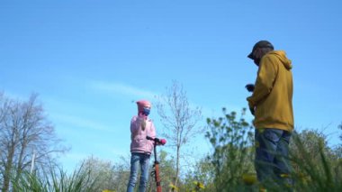 Mobiletli kız siyah maskeli emeklinin yanında duruyor.