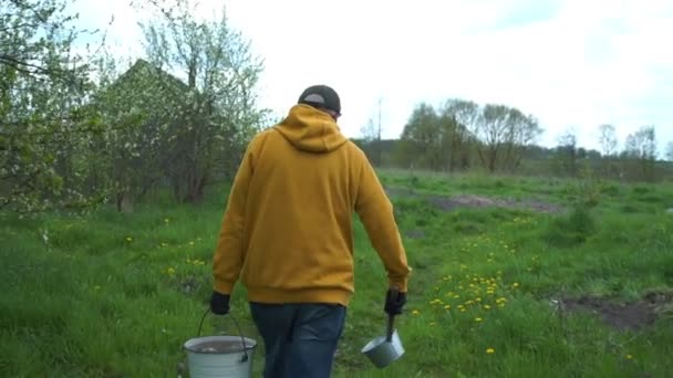 Çiftçi sebze bahçesini yıkamak için su kovasıyla yürür — Stok video