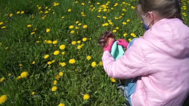 Молодая девушка в перчатках надевает одноразовую маску на лицо куклы — стоковое видео
