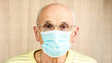 Mavi tek kullanımlık maske ve gözlüklü kel emekli.