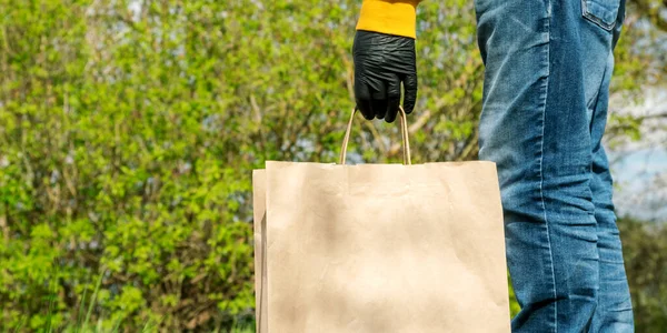 Person in schwarzen sterilen Handschuhen hält braune Papiertüte — Stockfoto