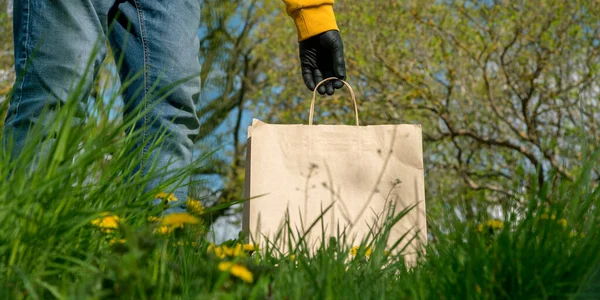 Alter Mann in schwarzen sterilen Handschuhen nimmt braune Papiertüte — Stockfoto