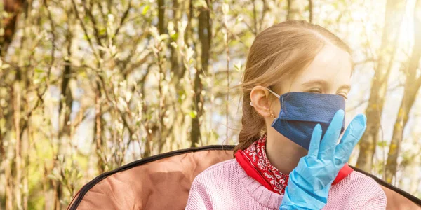 Молодая школьница в синих стерильных перчатках чинит маску в саду — стоковое фото