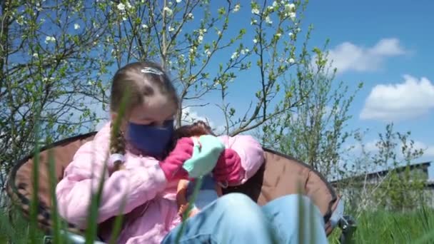 Meisje met vlecht zet masker op pop in zitten klapstoel — Stockvideo