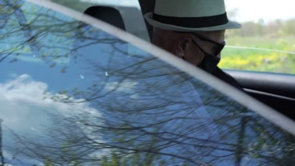 Conductor en sombrero y máscara se abrocha el cinturón de seguridad en el primer plano del coche — Vídeo de stock