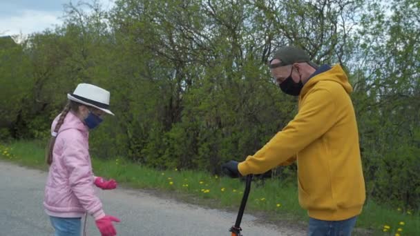 Tek kullanımlık maskeli kız büyükbaba scooter sürmeyi öğretiyor. — Stok video