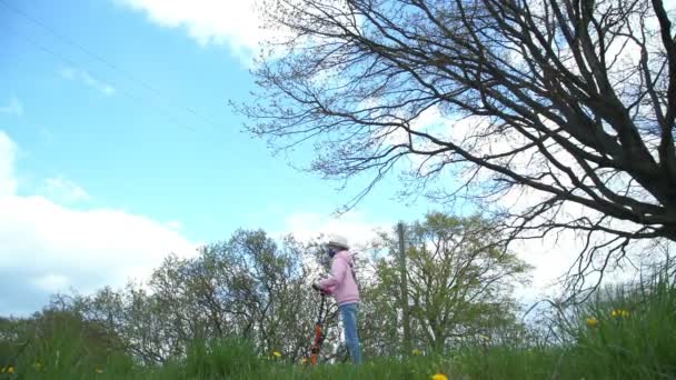 Flicka i mask rider skoter längs landsvägen under blå himmel — Stockvideo