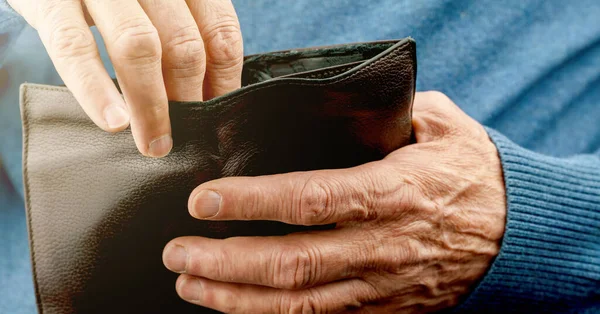poor old person in blue pullover opens black wallet closeup